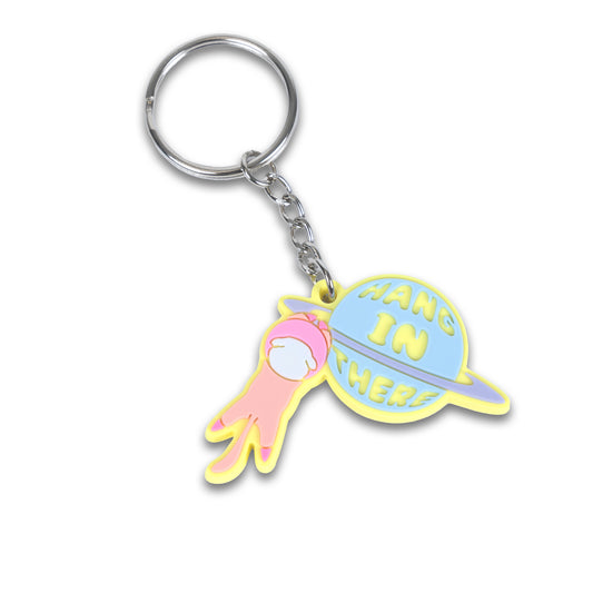 Photograph of Cute Cat Astronaut (Catstronaut) PVC Keychain, hanging onto a planet with cute phrase 'Hang In There'.