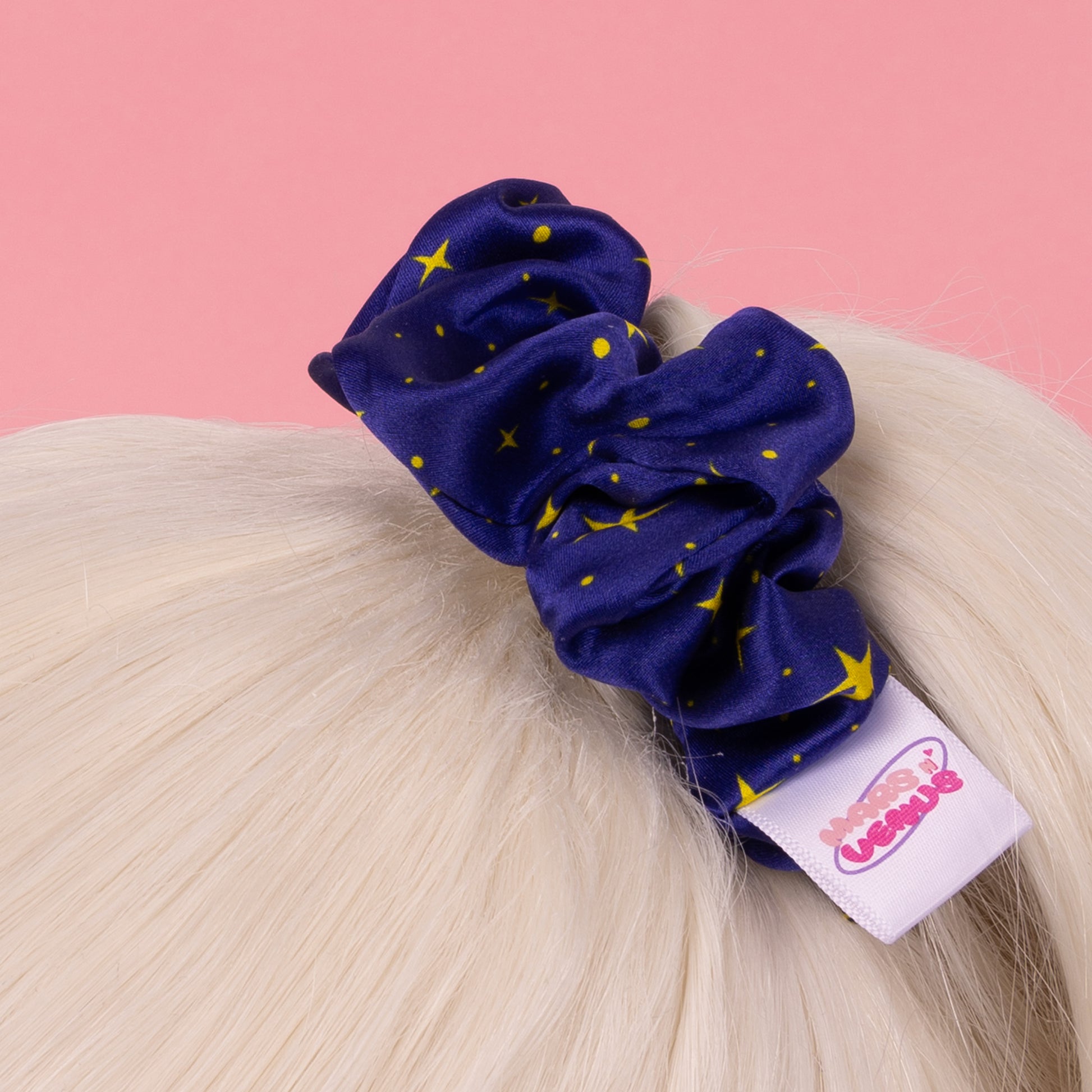 Photograph of Cute Mars N' Venus (MnV) starry silk hair scrunchie; featuring a Mars N' Venus (MnV) logo label; holding hair in a ponytail.
