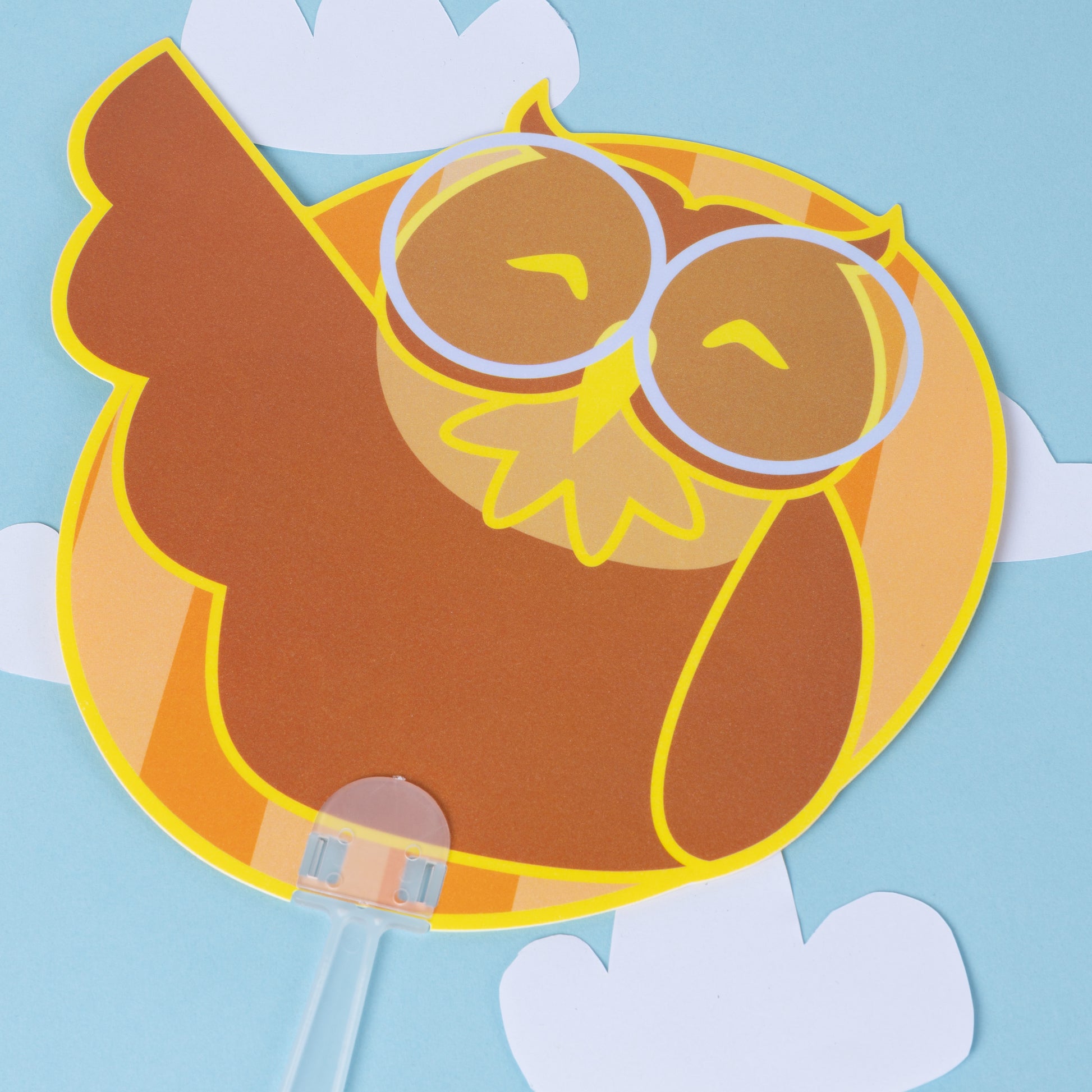 Photograph of handheld cute owl PVC fan featuring Professor Hoots on a blue cloudy background.